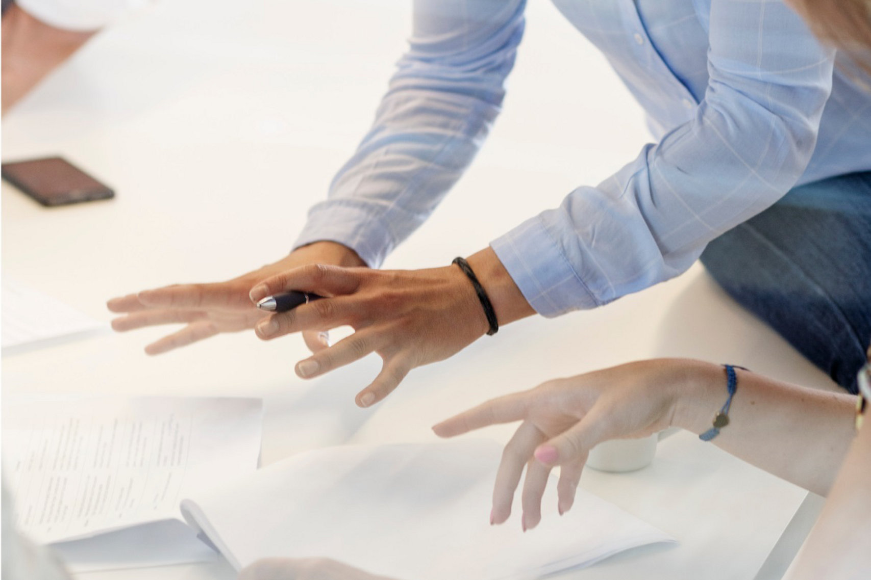 Discussion Hands emphasizing Idea Paper on the Table