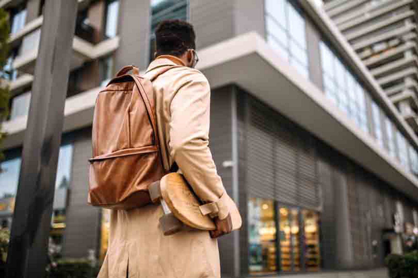 A man standing outdoors and carrying a bag and skateboard