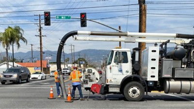 Workers in orange vests working on a manhole in the road