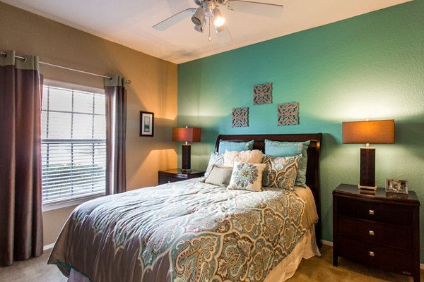 Bedroom with modern furnishings and large windows at Villas at Gateway Apartments