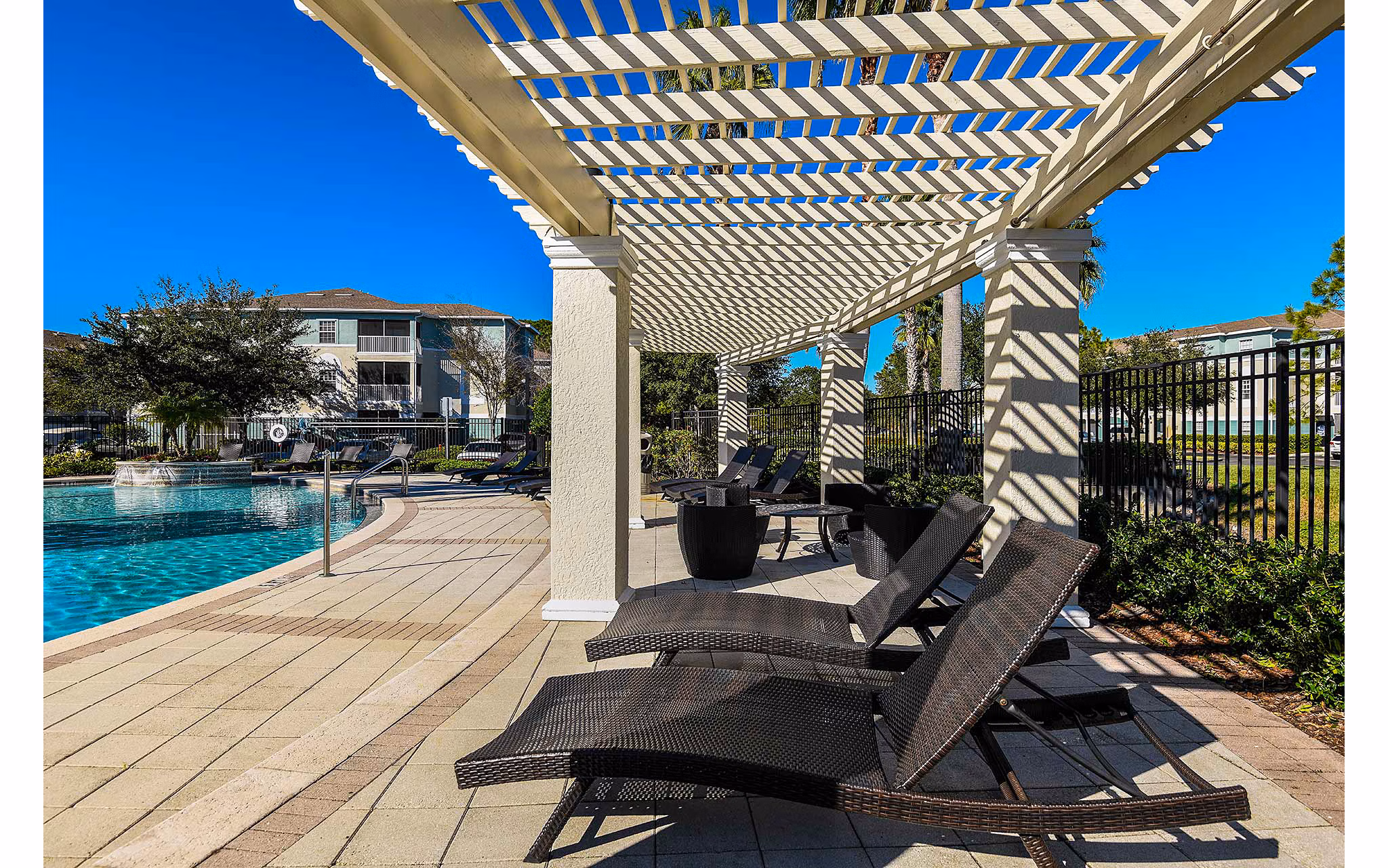 Poolside retreat at Villas at Gateway Apartments with modern lounge chairs and lush landscaping Ideal for relaxation in luxury living spaces