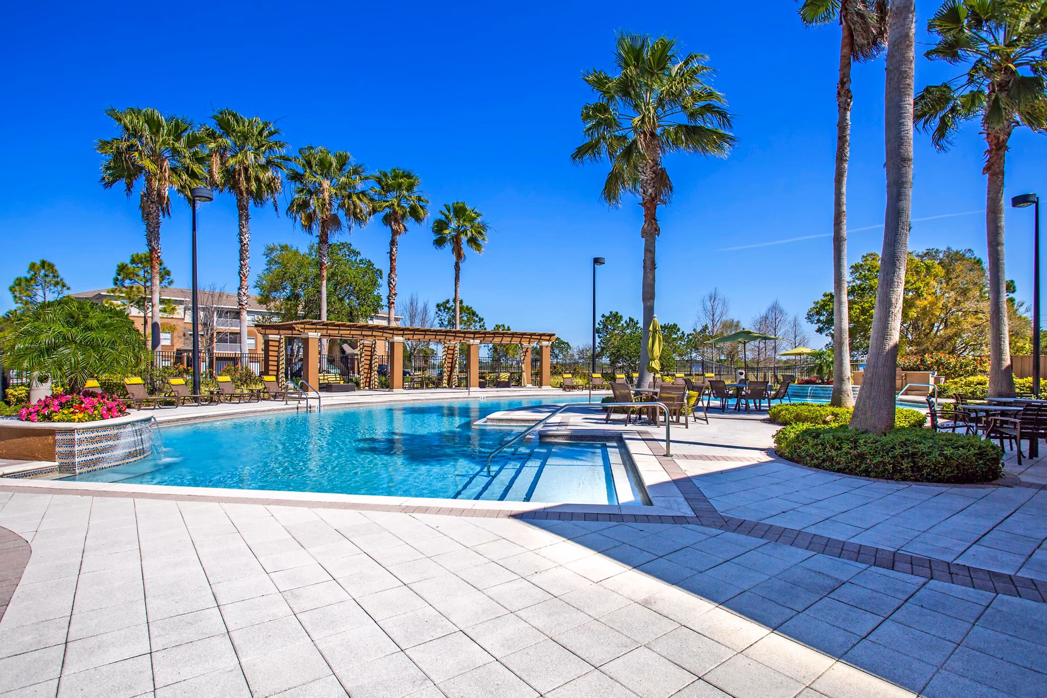 Modern poolside at Villas at Gateway Apartments with relaxed seating and lush landscaping