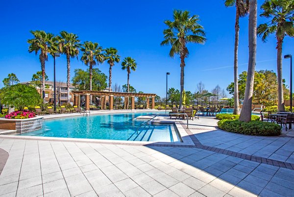 Modern poolside at Villas at Gateway Apartments with relaxed seating and lush landscaping