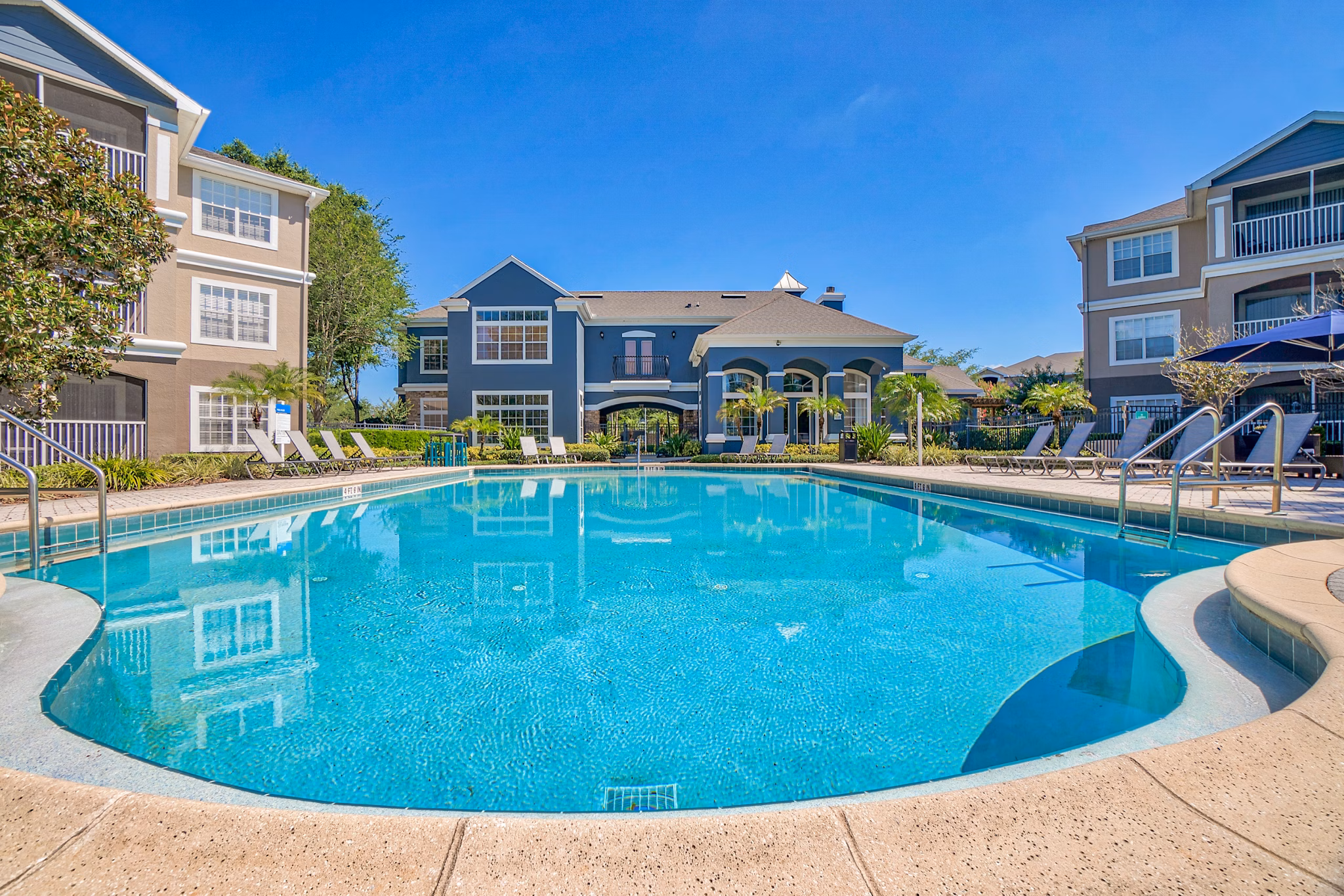 Resort-style pool with lounge chairs at Elmhurst Village Apartments