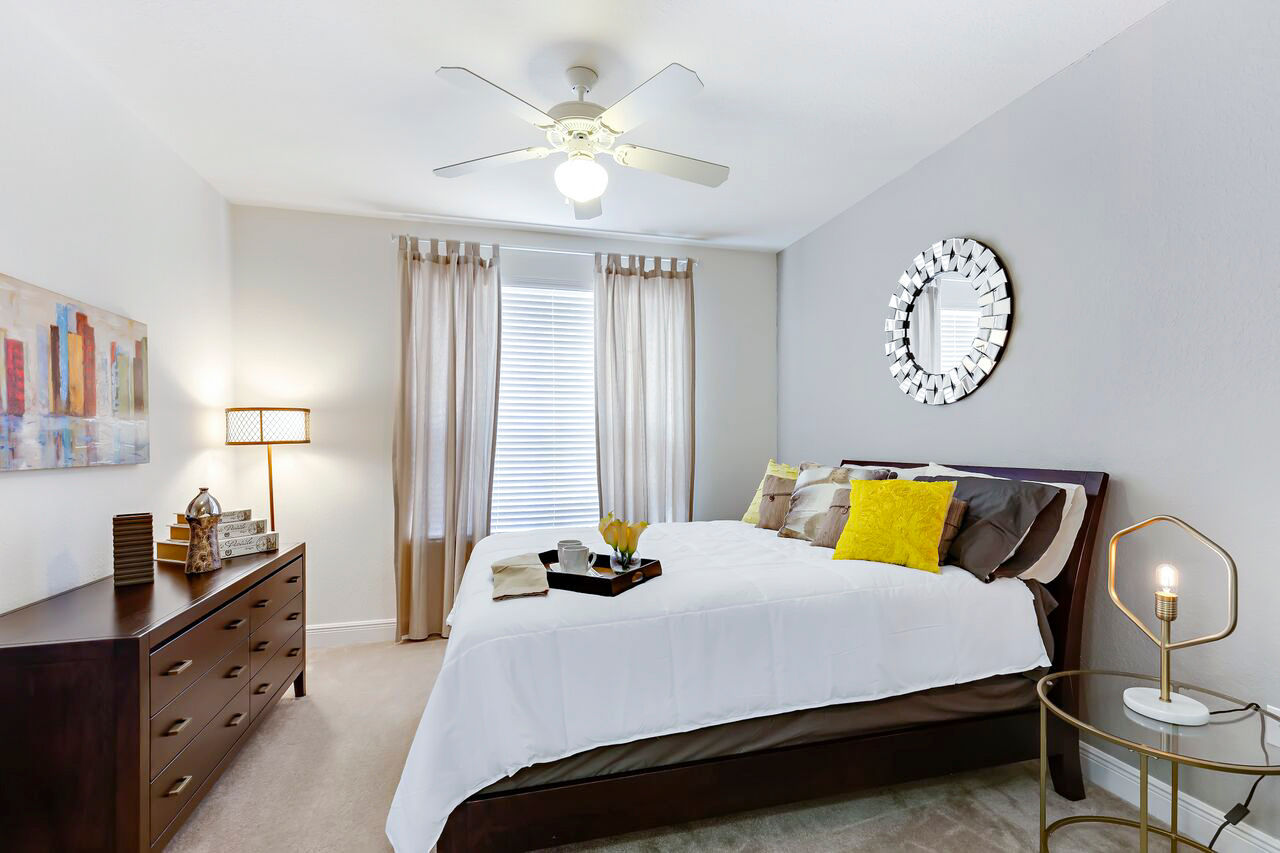 Cozy bedroom with modern decor at Trinity Club Apartments, featuring plush bedding and natural light for a luxurious living experience