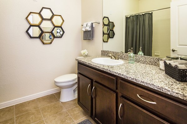 Bathroom with sleek fixtures and marble countertop at Trinity Club Apartments