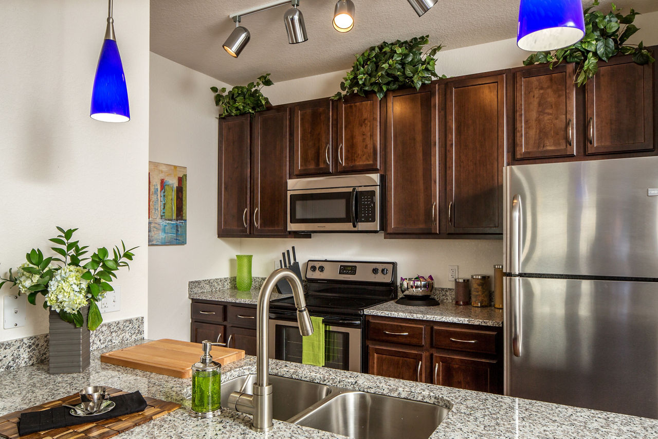 Modern kitchen with stainless steel appliances and granite countertops at Trinity Club Apartments