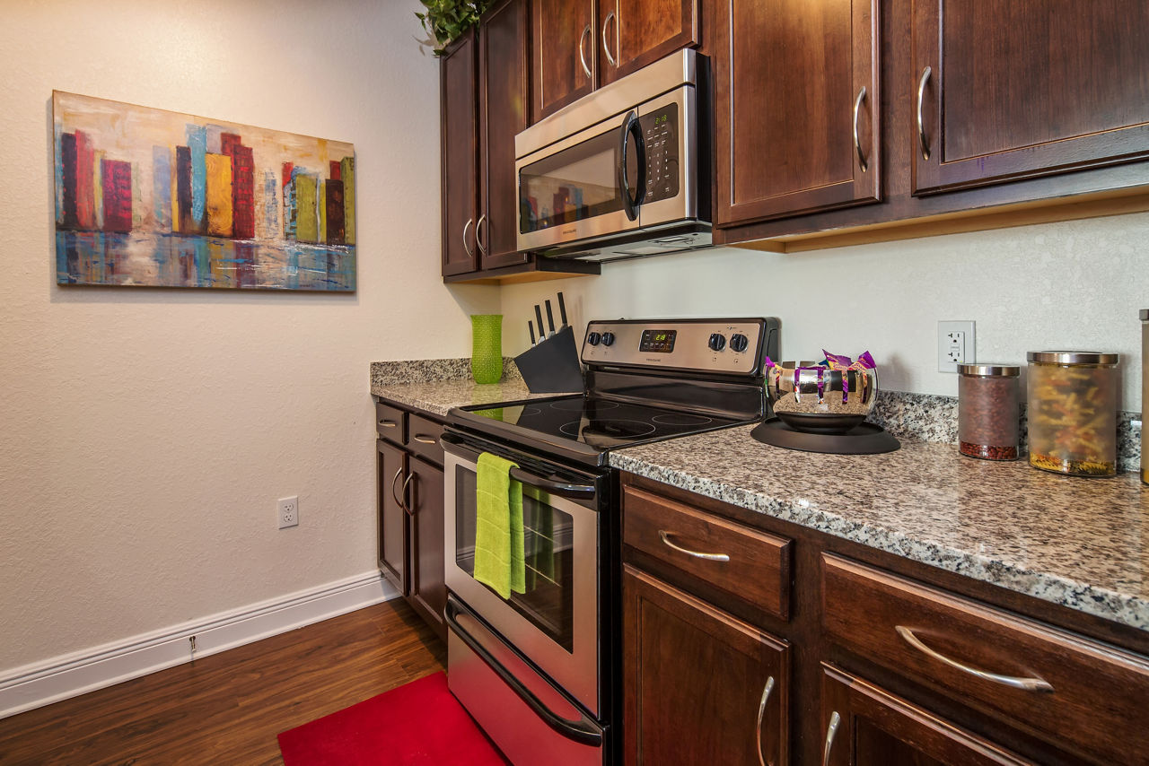 Modern kitchen with stainless steel appliances and granite countertops at Trinity Club Apartments