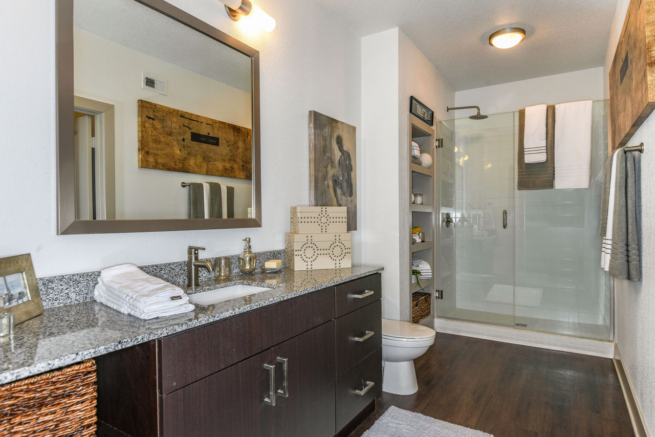 Modern bathroom featuring dual sinks and granite countertops at The Gallery at Mills Park Apartments