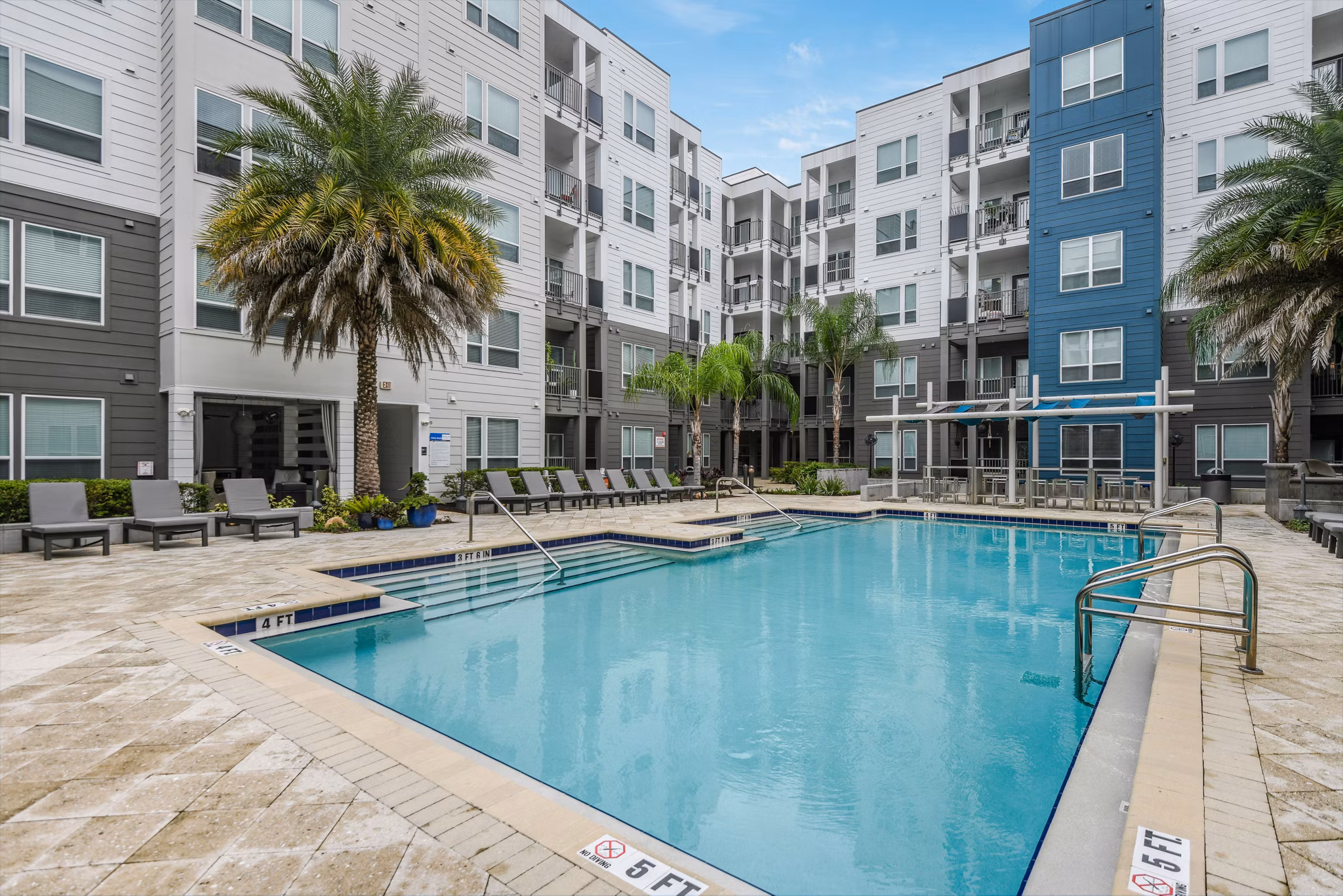Sparkling outdoor pool area at The Gallery at Mills Park Apartments, offering a serene escape with stylish lounging and relaxation spaces