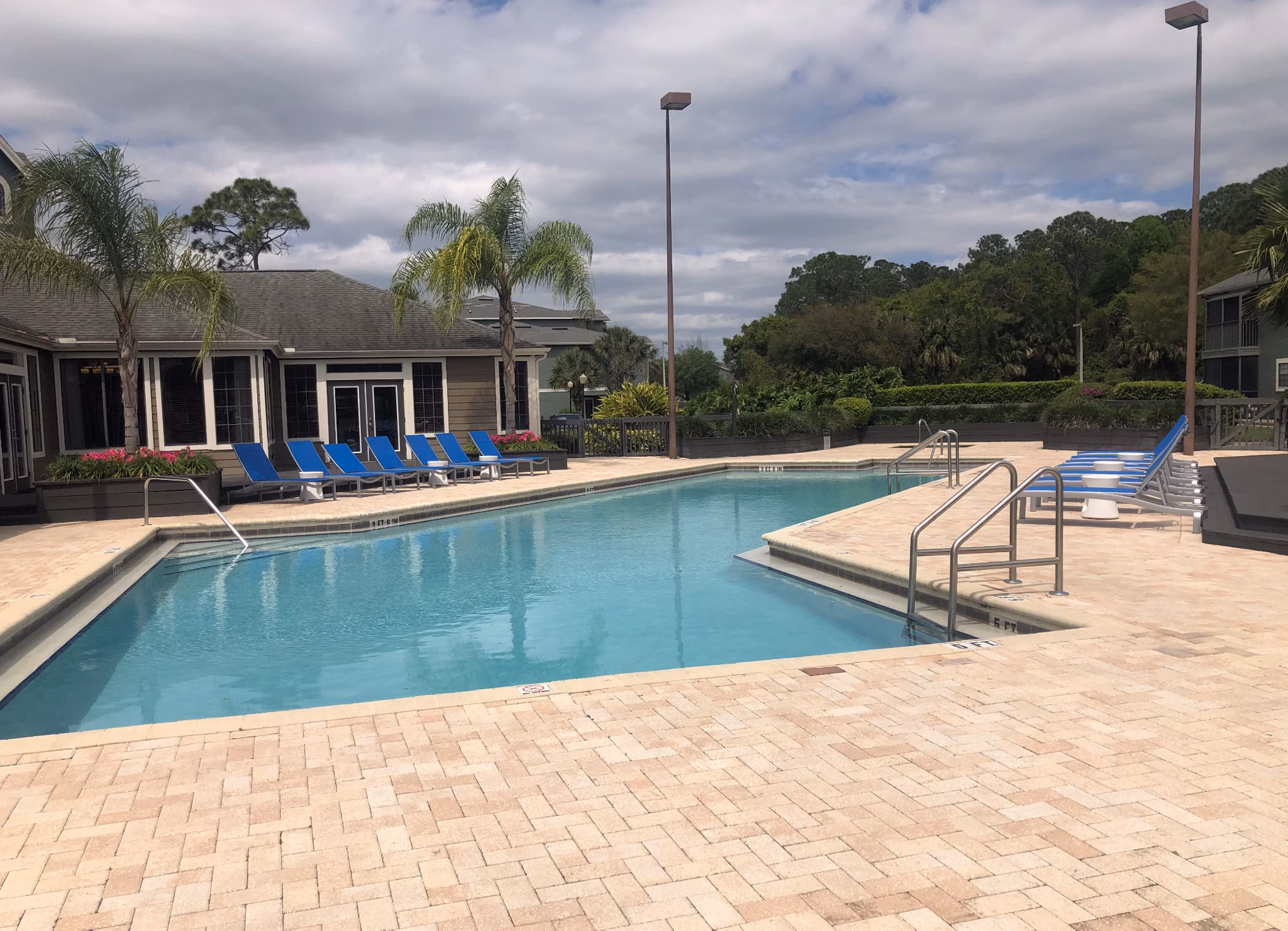Modern outdoor pool at Stonebrook Apartments featuring sun loungers and landscaped gardens