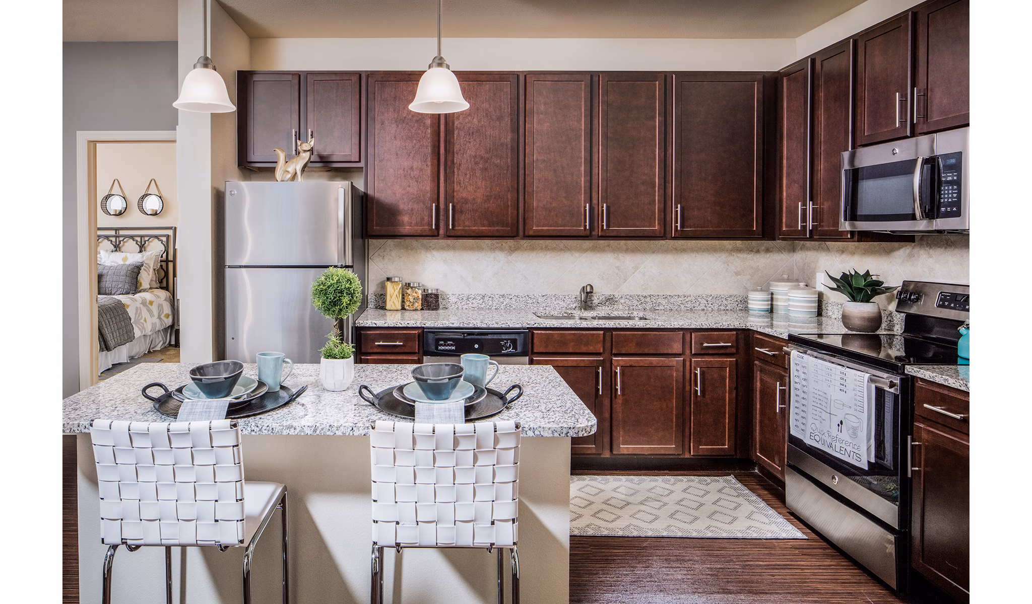 Modern kitchen with granite countertops and stainless steel appliances in Sanctuary at West Port Apartments
