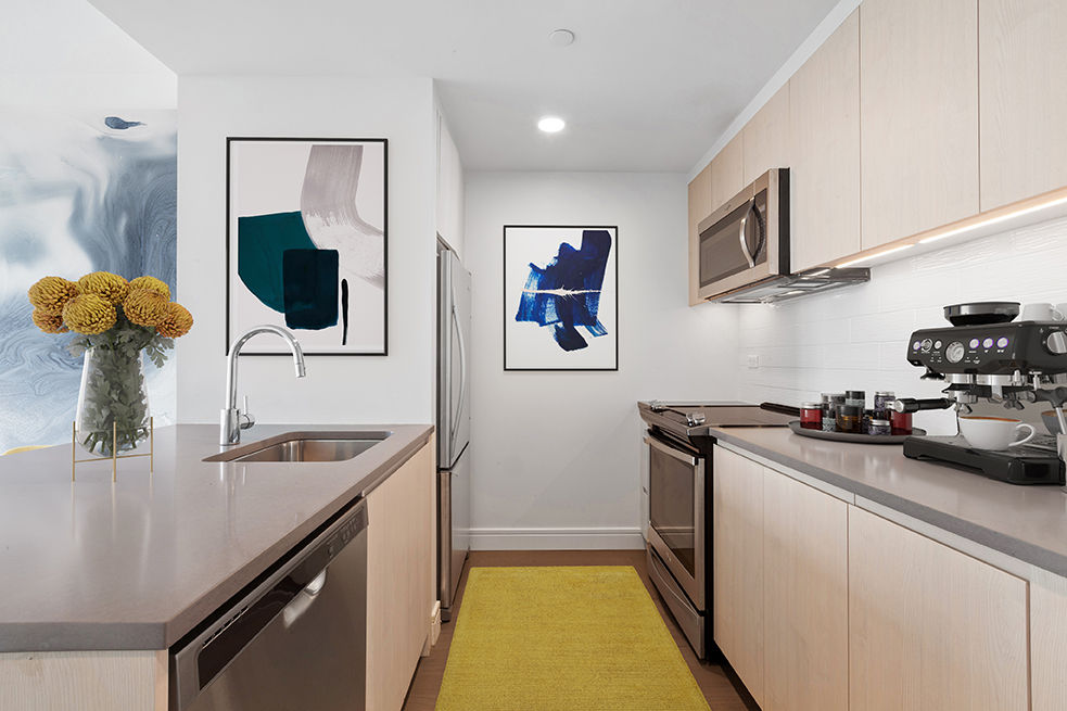 Modern kitchen featuring sleek stainless steel appliances and granite countertops in Watermark LIC luxury apartments
