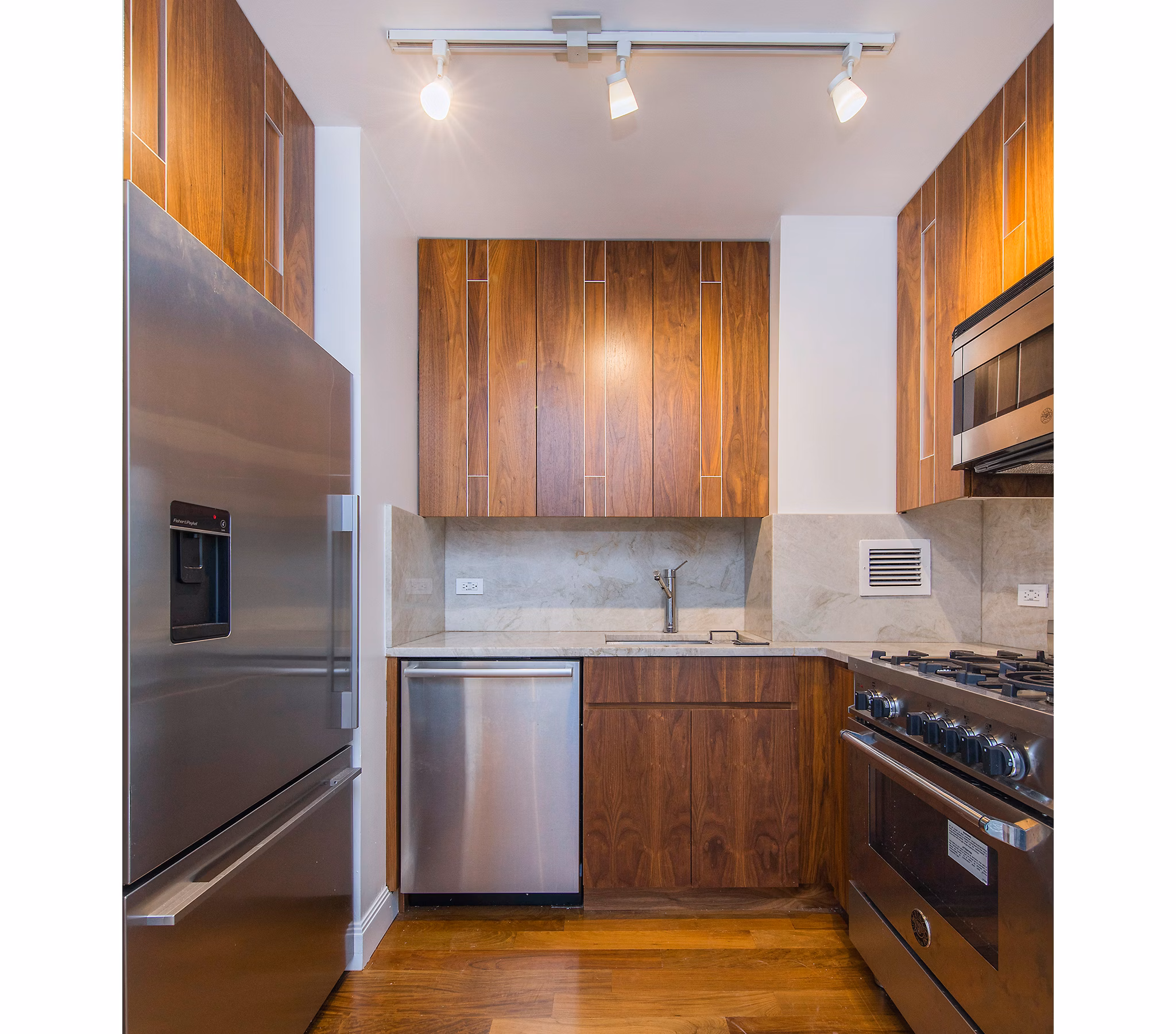 Modern kitchen featuring stainless steel appliances and granite countertops at INSTRATA Gramercy Apartments