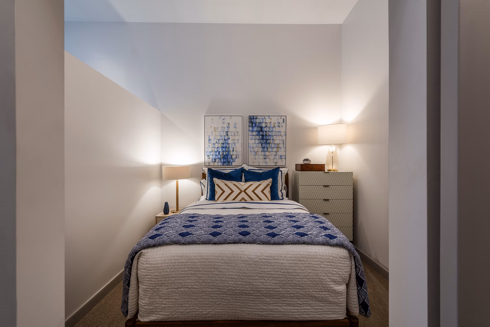 Cozy bedroom featuring a stylish bed, two lamps, dresser, and artwork in luxury apartment