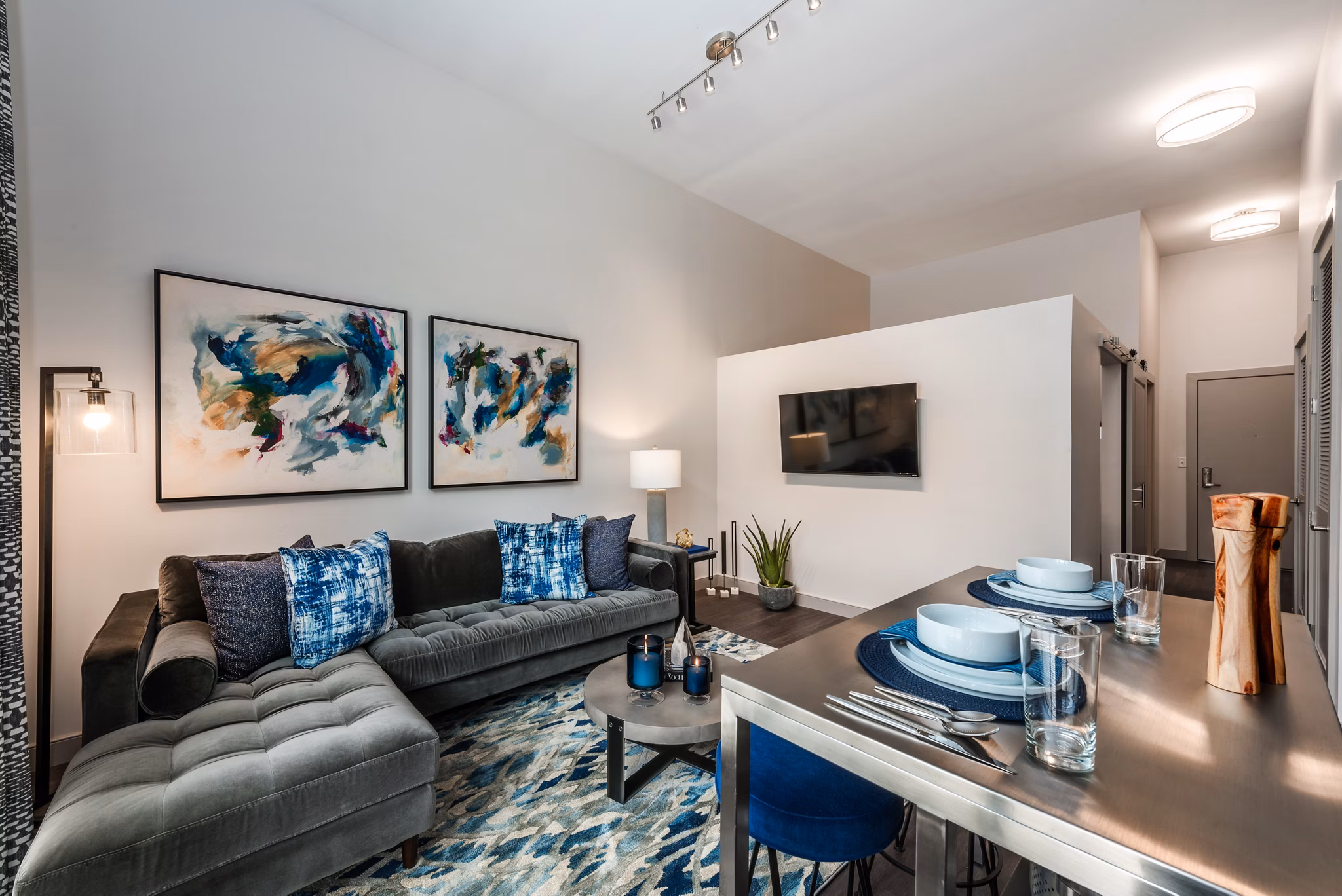 Modern living room and dining area with sectional sofa, abstract art, and dining table set in luxury apartments