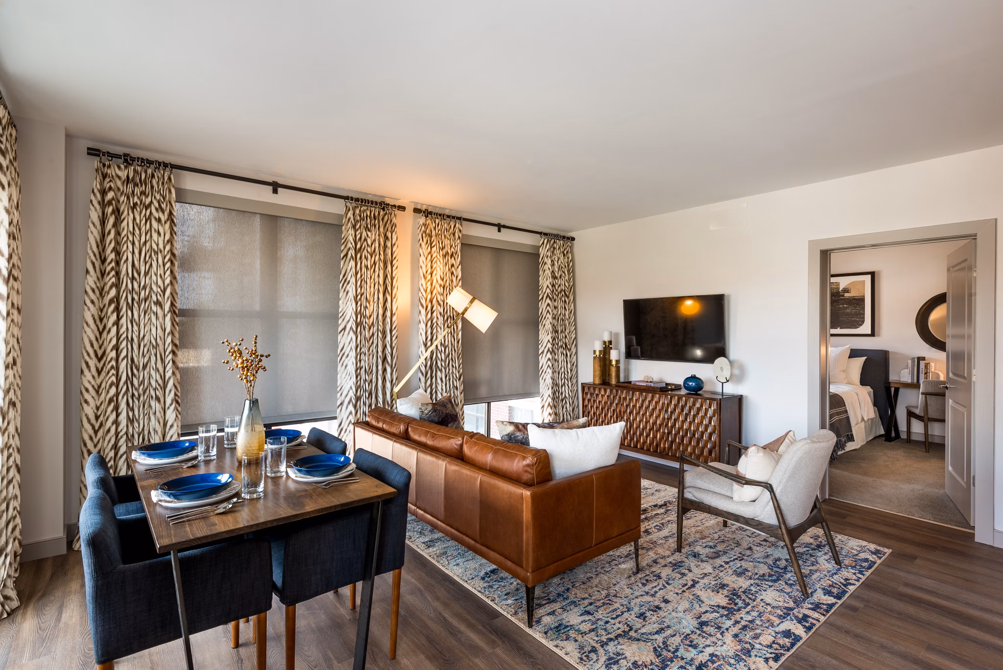 Modern living room and dining area with leather sofa and blue place settings in luxury apartment