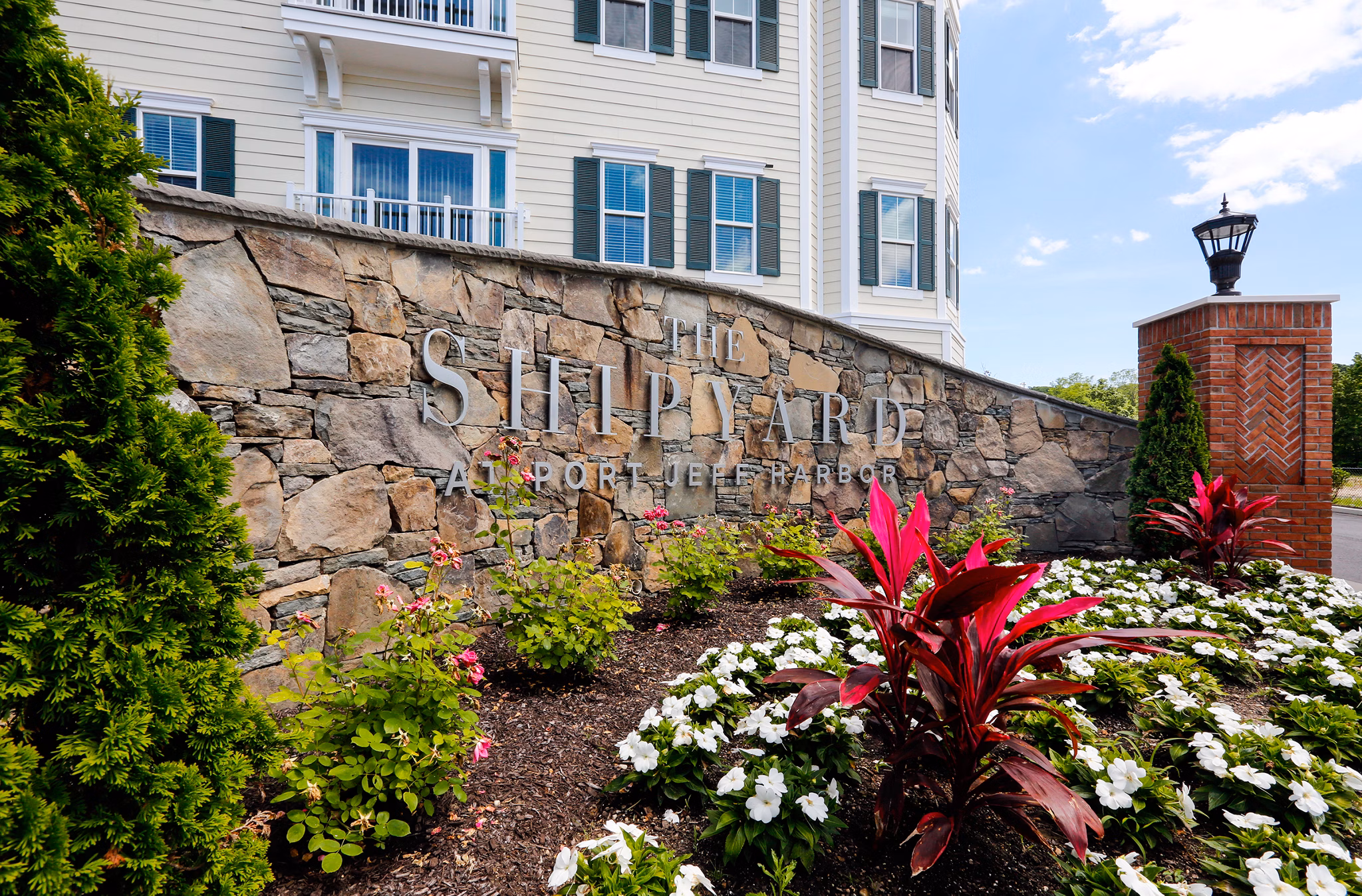 The Shipyard at Port Jeff Harbor: Beautifully landscaped area with stone wall and colorful flowers