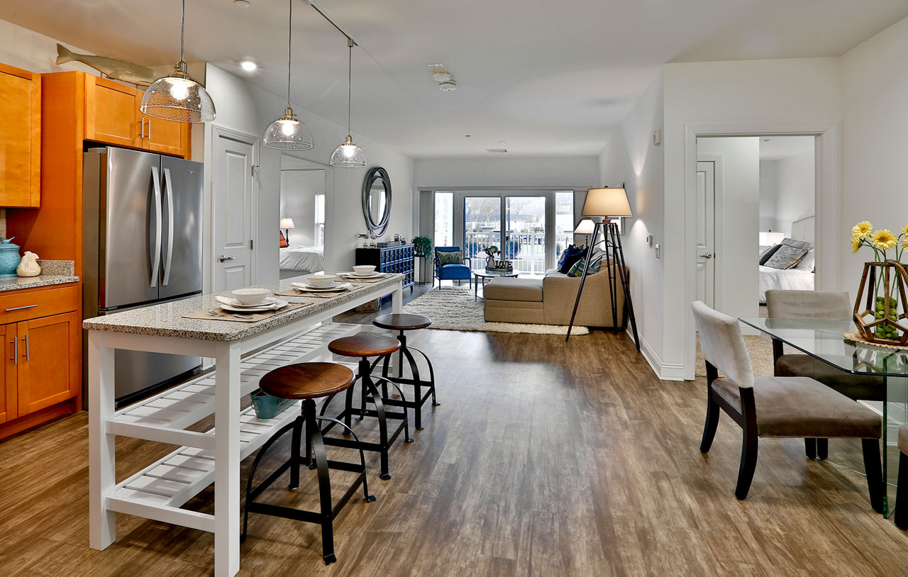 Dining room with elegant chandelier and hardwood floors at The Shipyard at Port Jefferson Harbor Apartments