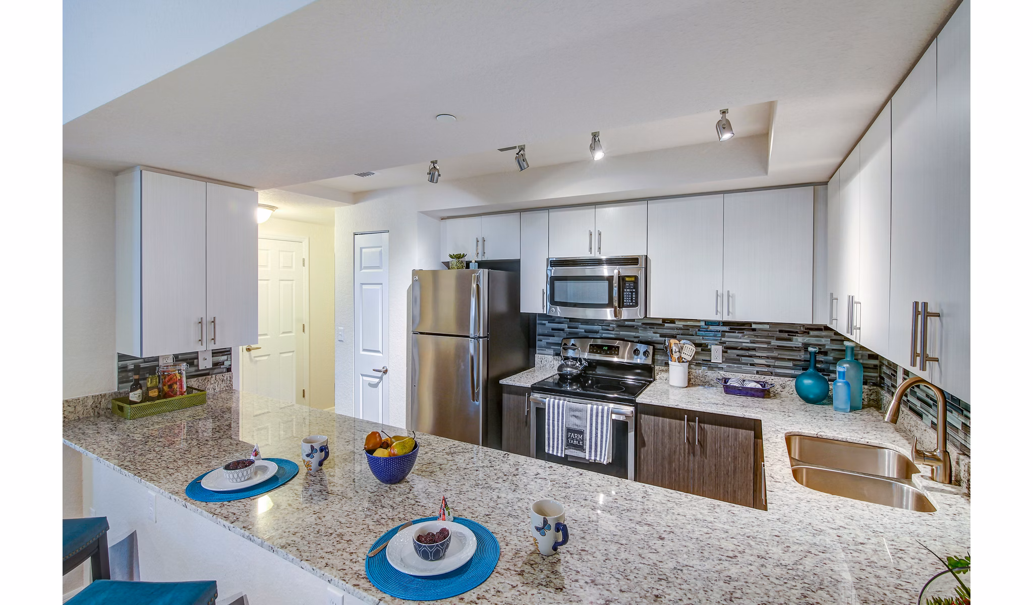 Modern kitchen with island and stainless steel appliances at The Quaye at Palm Beach Gardens Apartments