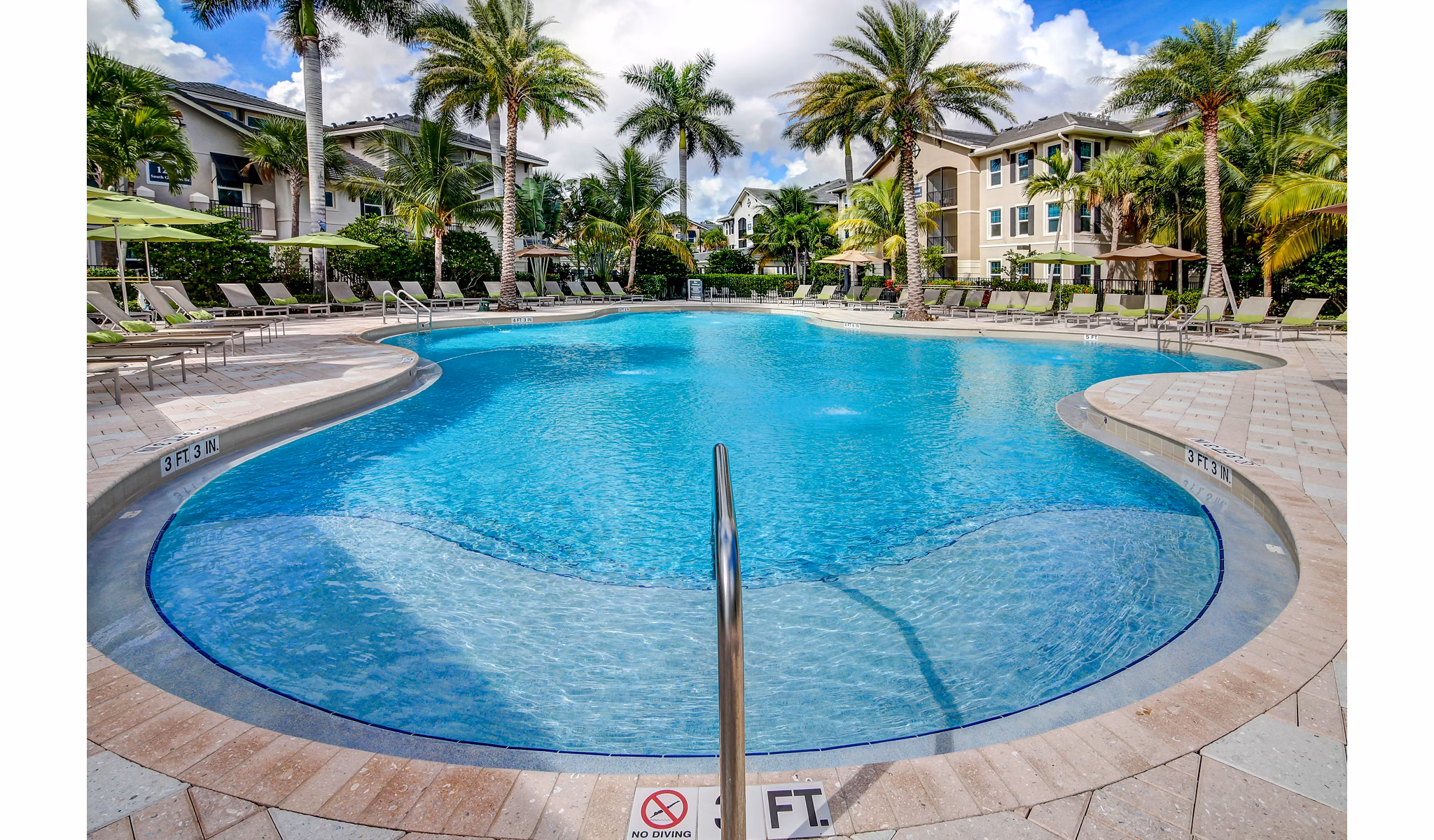 Resort-style pool with palm trees at The Quaye at Palm Beach Gardens Apartments