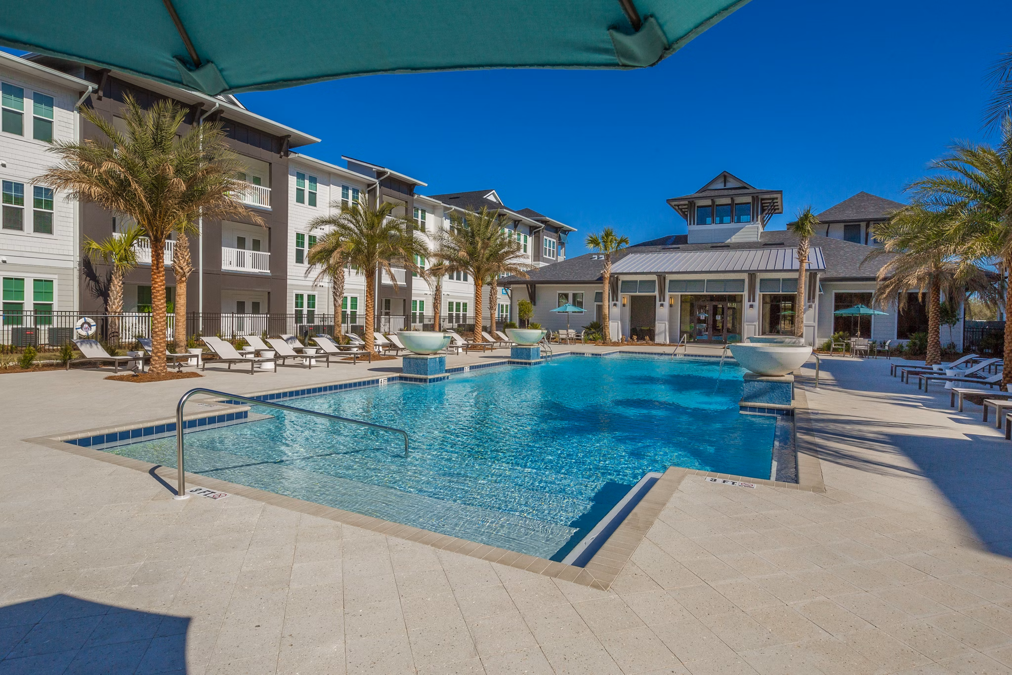 Resort-style pool at Sea Glass Apartments featuring lounge chairs and poolside cabanas