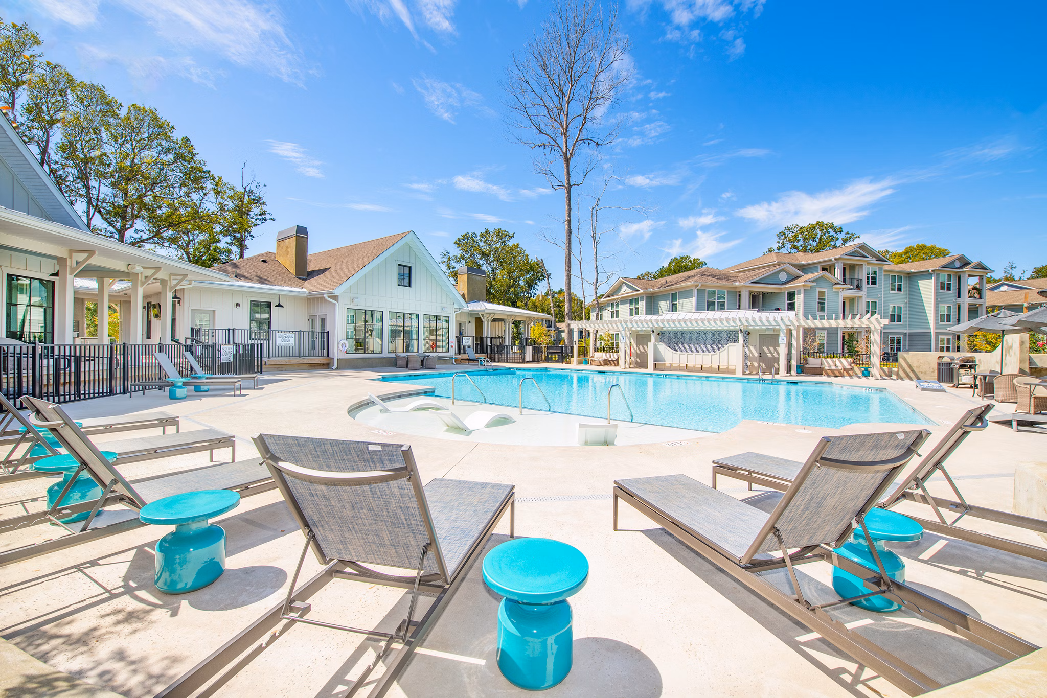 Sunlit swimming pool at Atlantic at Grand Oaks Apartments with lush greenery in the background, offering a relaxing oasis for residents