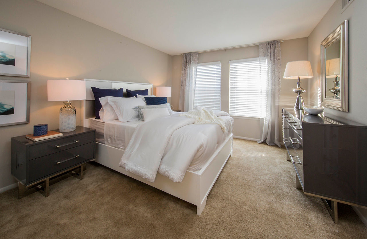 Cozy bedroom with large windows at Lakeside Mill Apartments