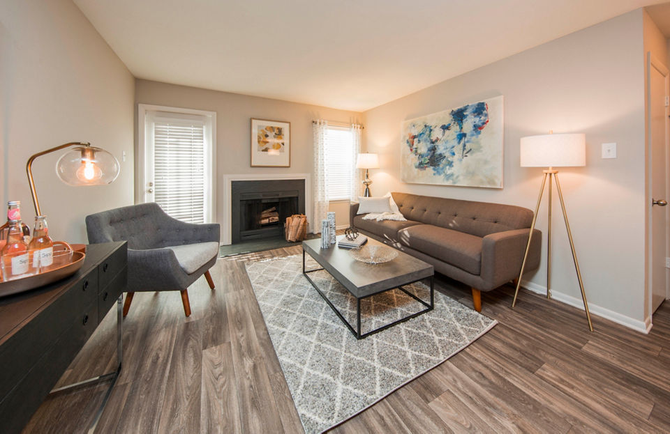 Spacious living room with modern decor in Lakeside Mill Apartments, featuring comfy seating and large windows