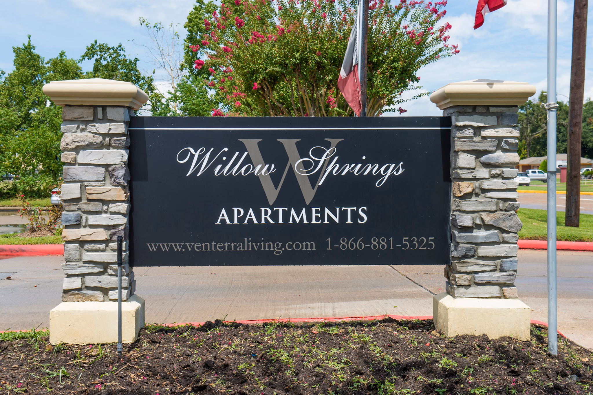 Signage at Willow Springs Apartments: Elegant entry sign with lush landscaping in luxury residential community