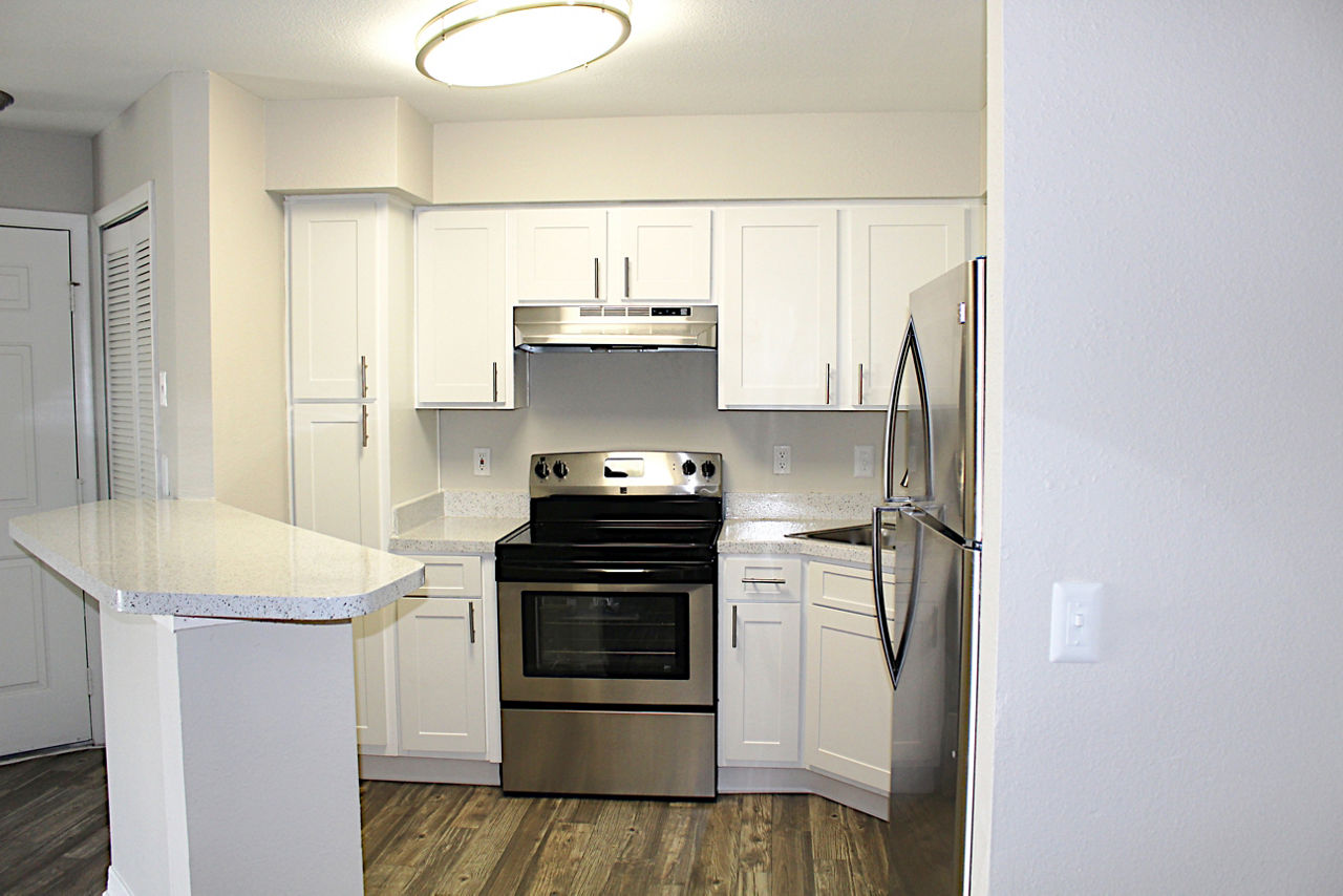 Modern kitchen with stainless steel appliances and marble countertops at Island Club Apartments