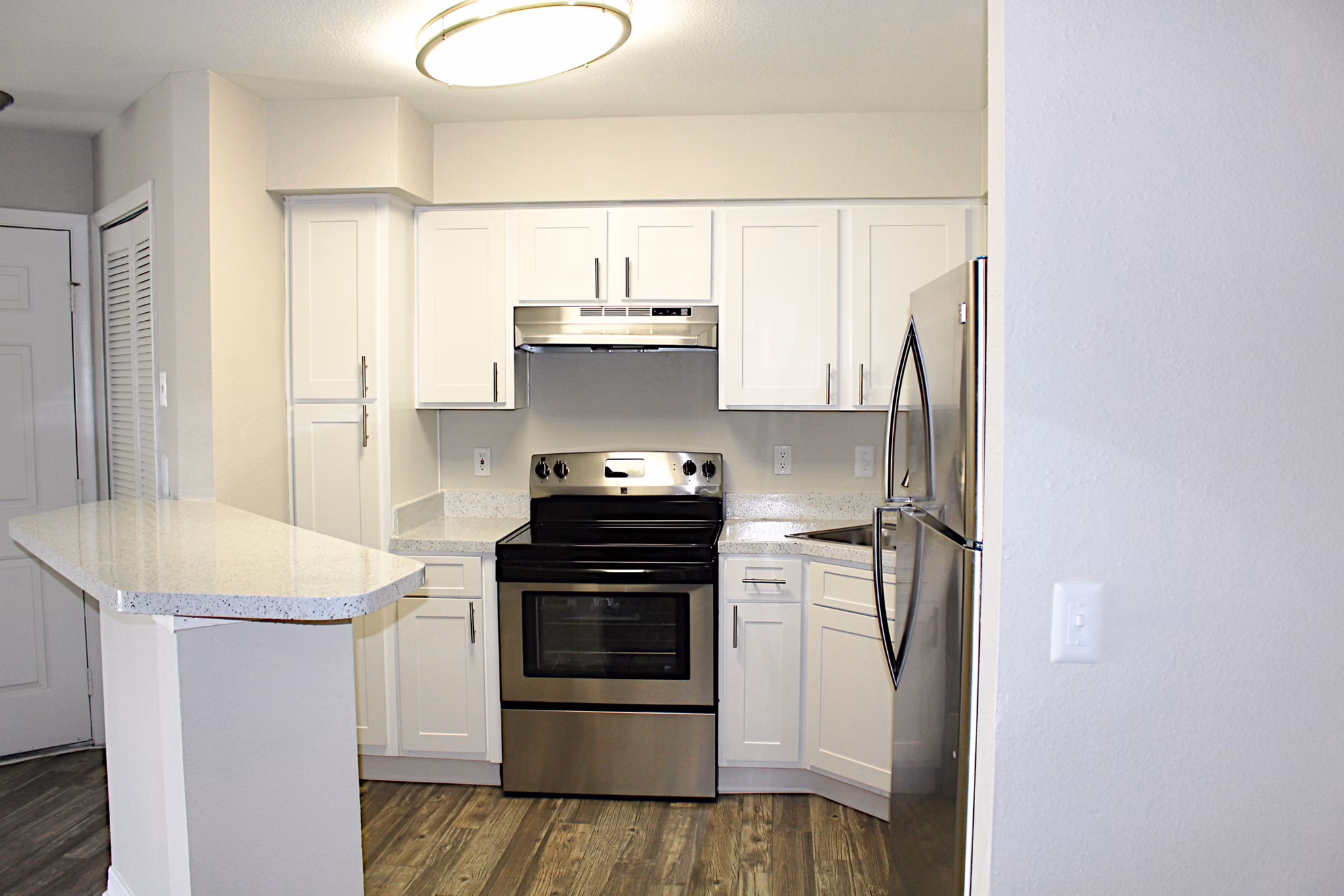 Modern kitchen with stainless steel appliances and marble countertops at Island Club Apartments