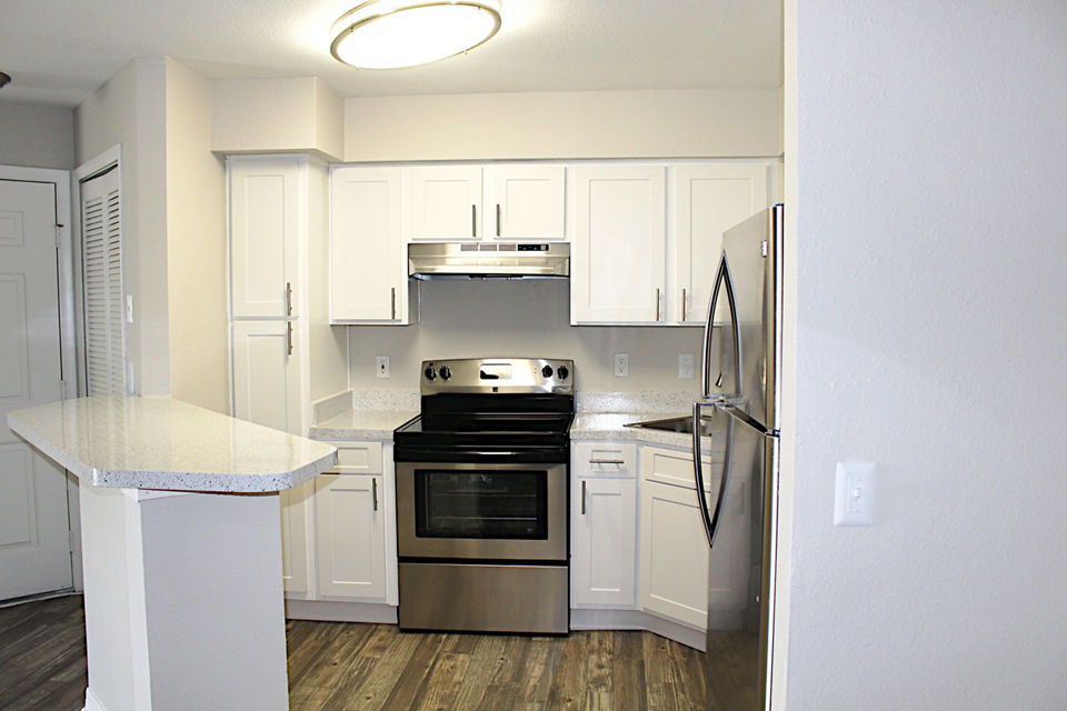 Modern kitchen with stainless steel appliances and marble countertops at Island Club Apartments