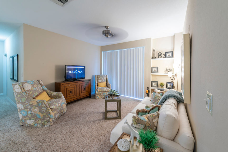 Living room with elegant decor and bay window at Legacy On The Bay Apartments, luxury apartment community by Greystar