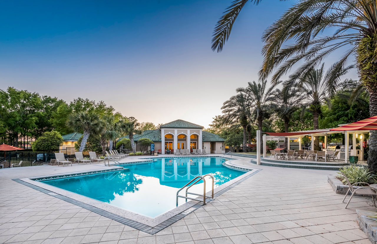 Resort-style pool area with palm trees at Legacy On The Bay Apartments