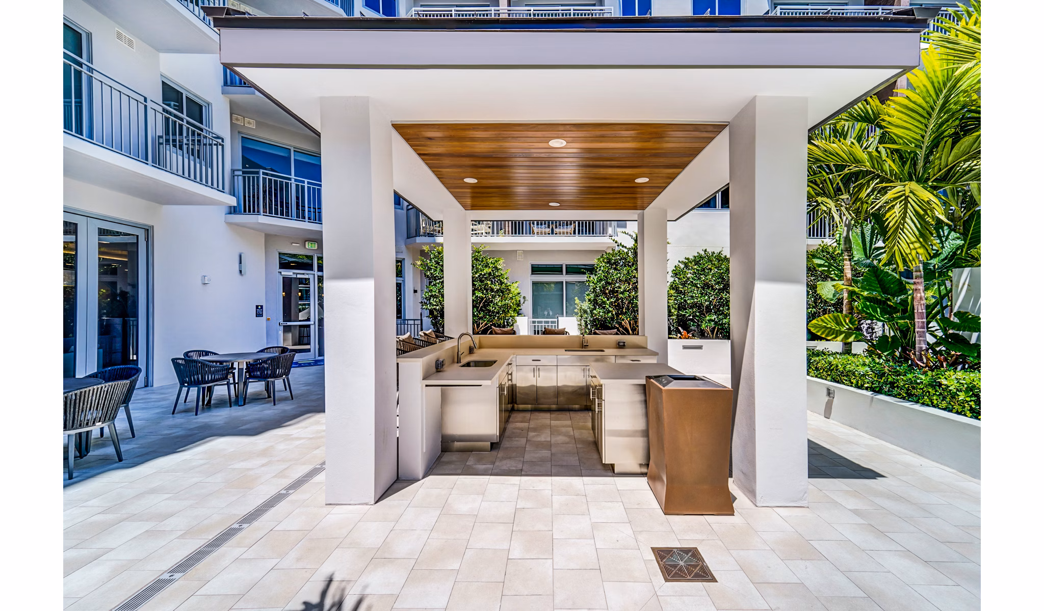 Serene courtyard at Oversea at Flagler Banyan Square Apartments featuring lush landscaping and seating areas