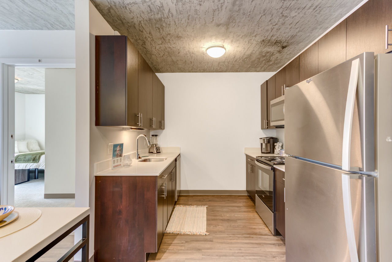 Modern kitchen with dark wood cabinets and stainless steel appliances at luxury apartments