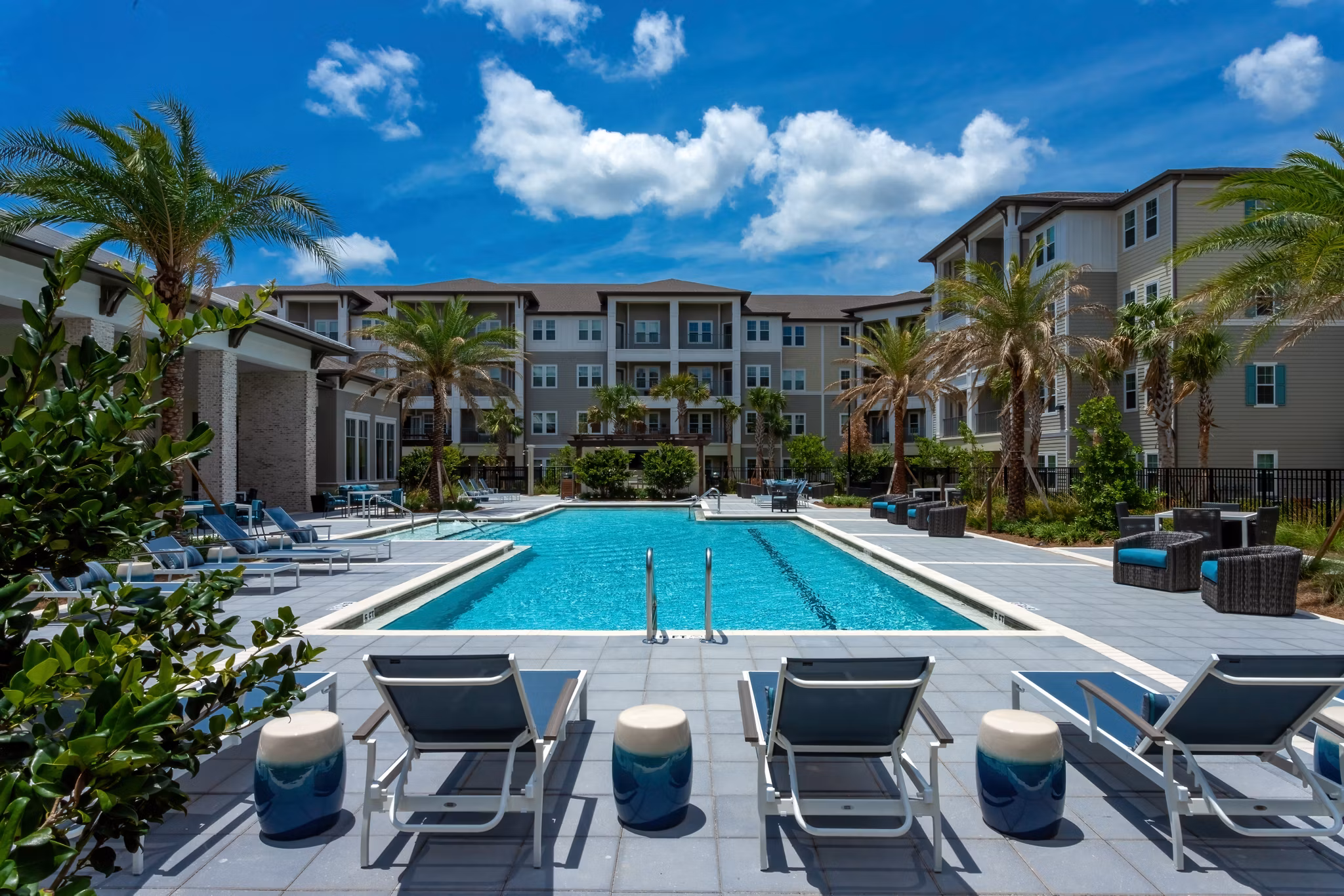 Modern swimming pool at Overture Hamlin Apartments featuring lounge areas and lush surroundings