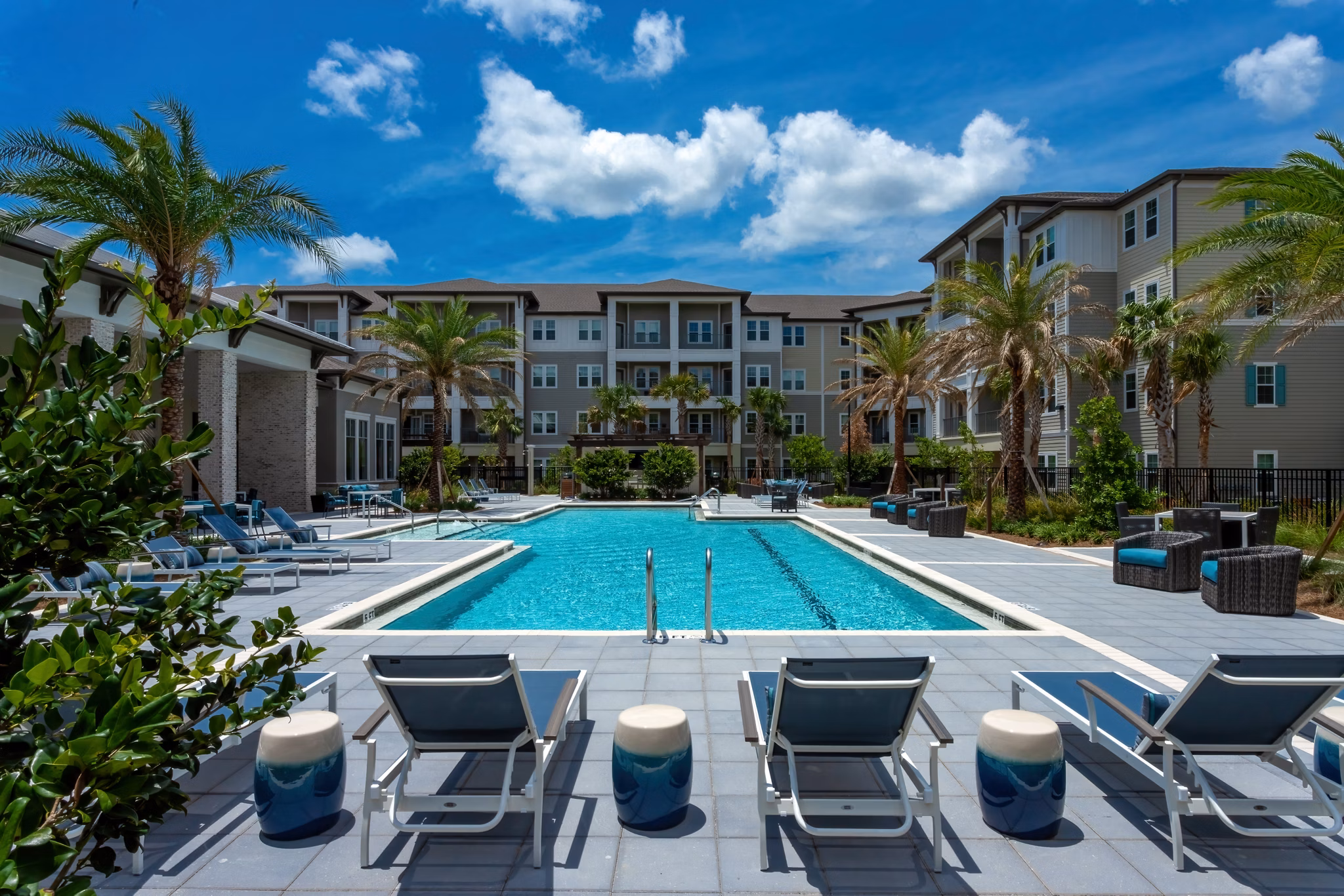 Modern swimming pool at Overture Hamlin Apartments featuring lounge areas and lush surroundings