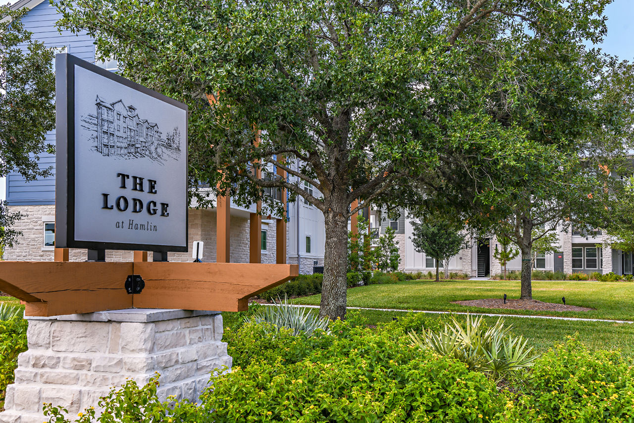 The Lodge at Hamlin sign with lush trees in a serene setting near luxury apartments
