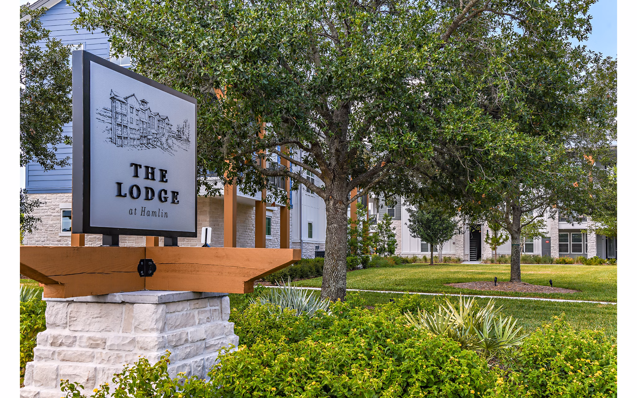 The Lodge at Hamlin sign with lush trees in a serene setting near luxury apartments