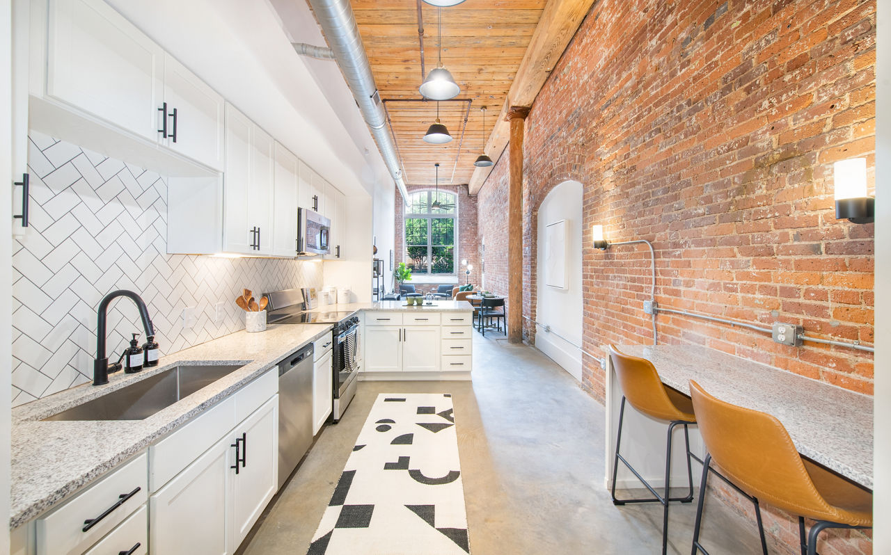 Spacious kitchen featuring modern appliances and granite countertops in The Lofts at Woodside Mill Apartments