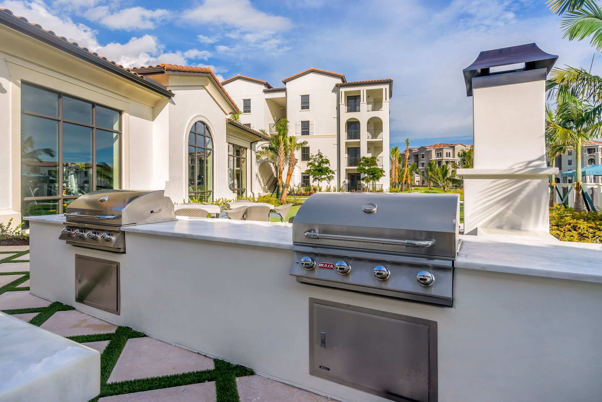 Outdoor grill area at Lago Apartments with modern seating and lush greenery, perfect for social gatherings