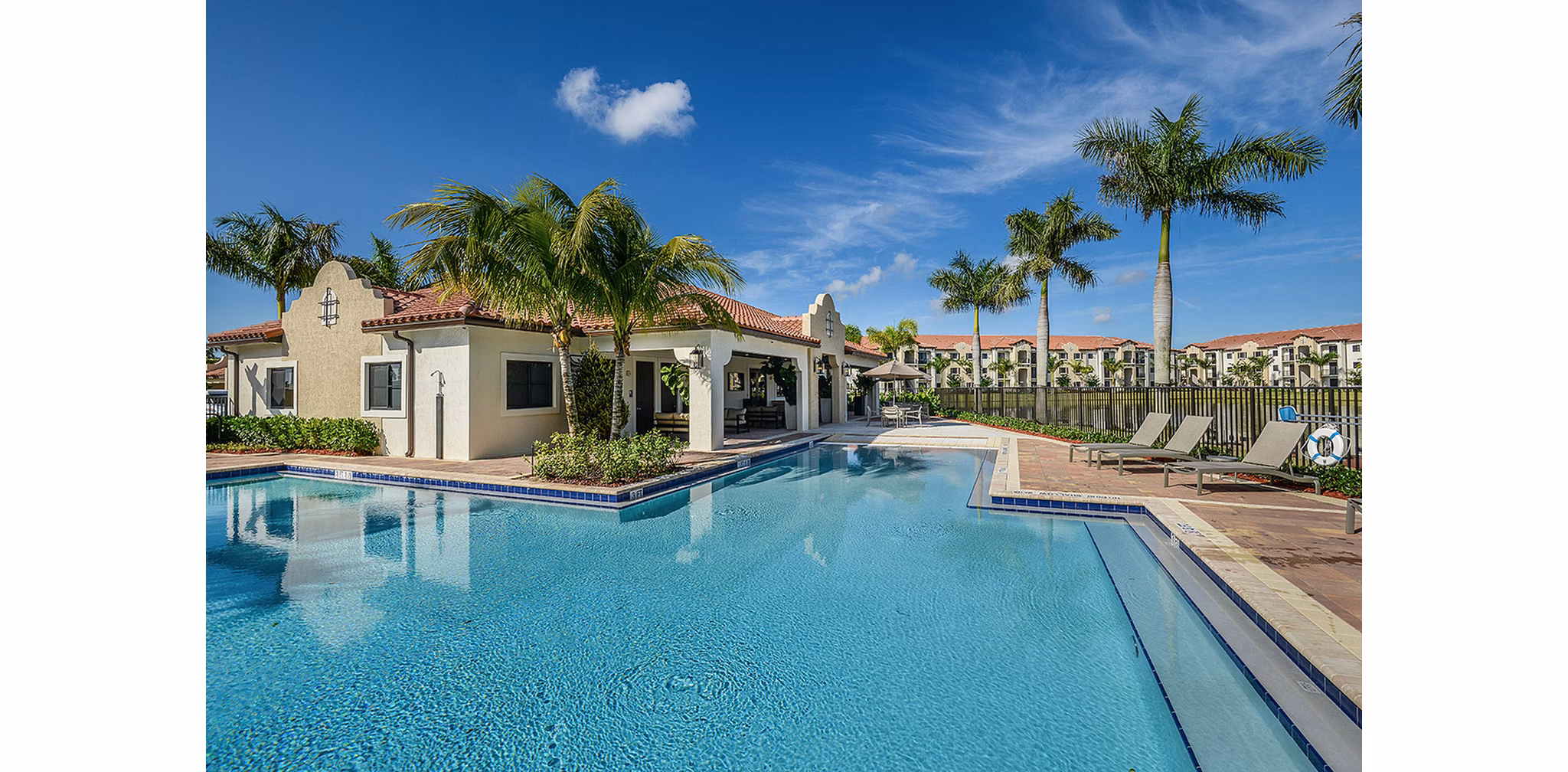 Resort-style swimming pool at Celebration Pointe Apartments with lush landscaping and comfortable loungers ideal for relaxation and leisure