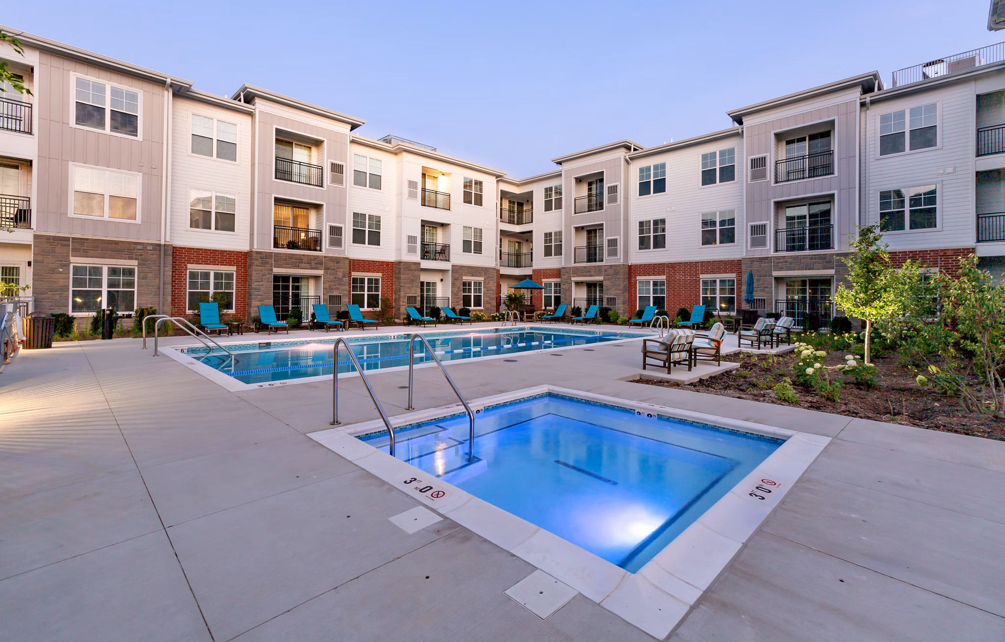 Luxury poolside lounging area at Avenida Naperville Apartments with chic sun loungers and vibrant landscaping