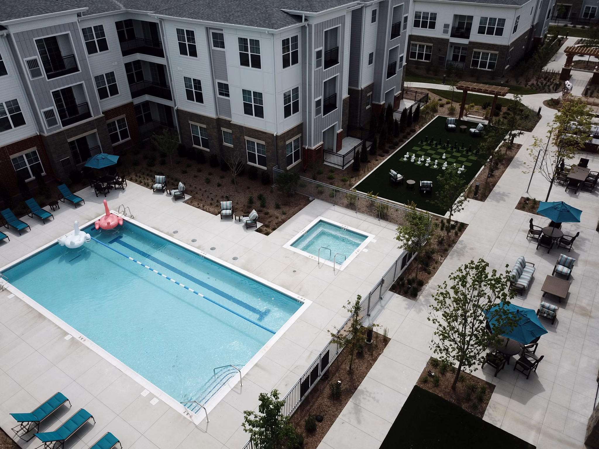 Luxury apartment complex featuring a pool, hot tub, and lounge seating in a vibrant outdoor area