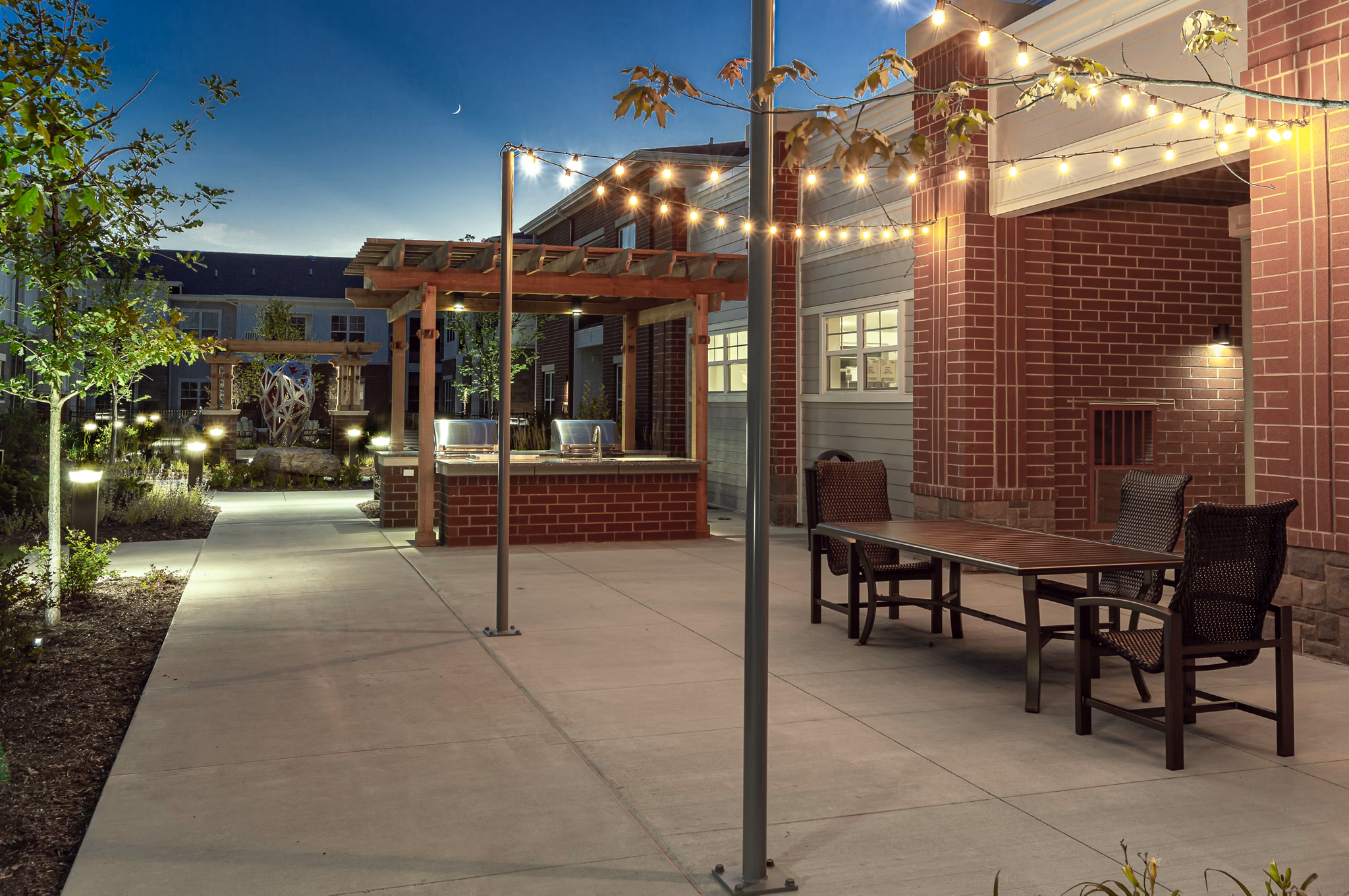 Outdoor patio area with cozy seating and lush greenery at Avenida Naperville Apartments, ideal for relaxation and social gatherings