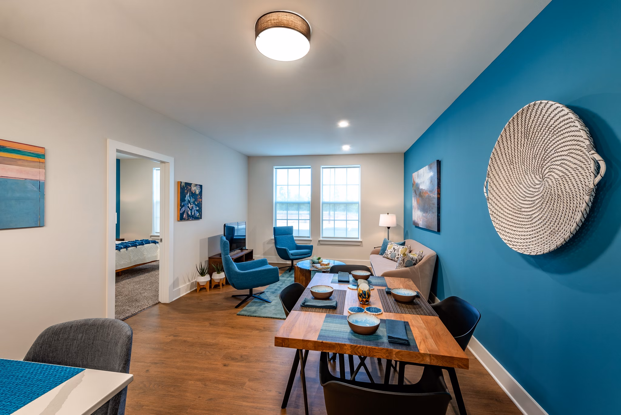 Modern living and dining area with blue accent walls and wooden flooring in luxury apartments