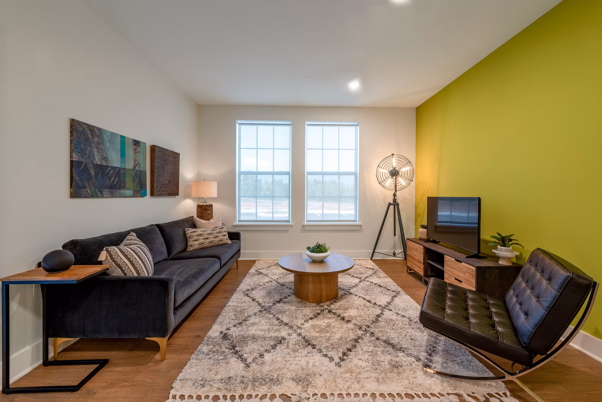 Modern living room featuring a sofa, coffee table, and green accent wall in luxury apartments