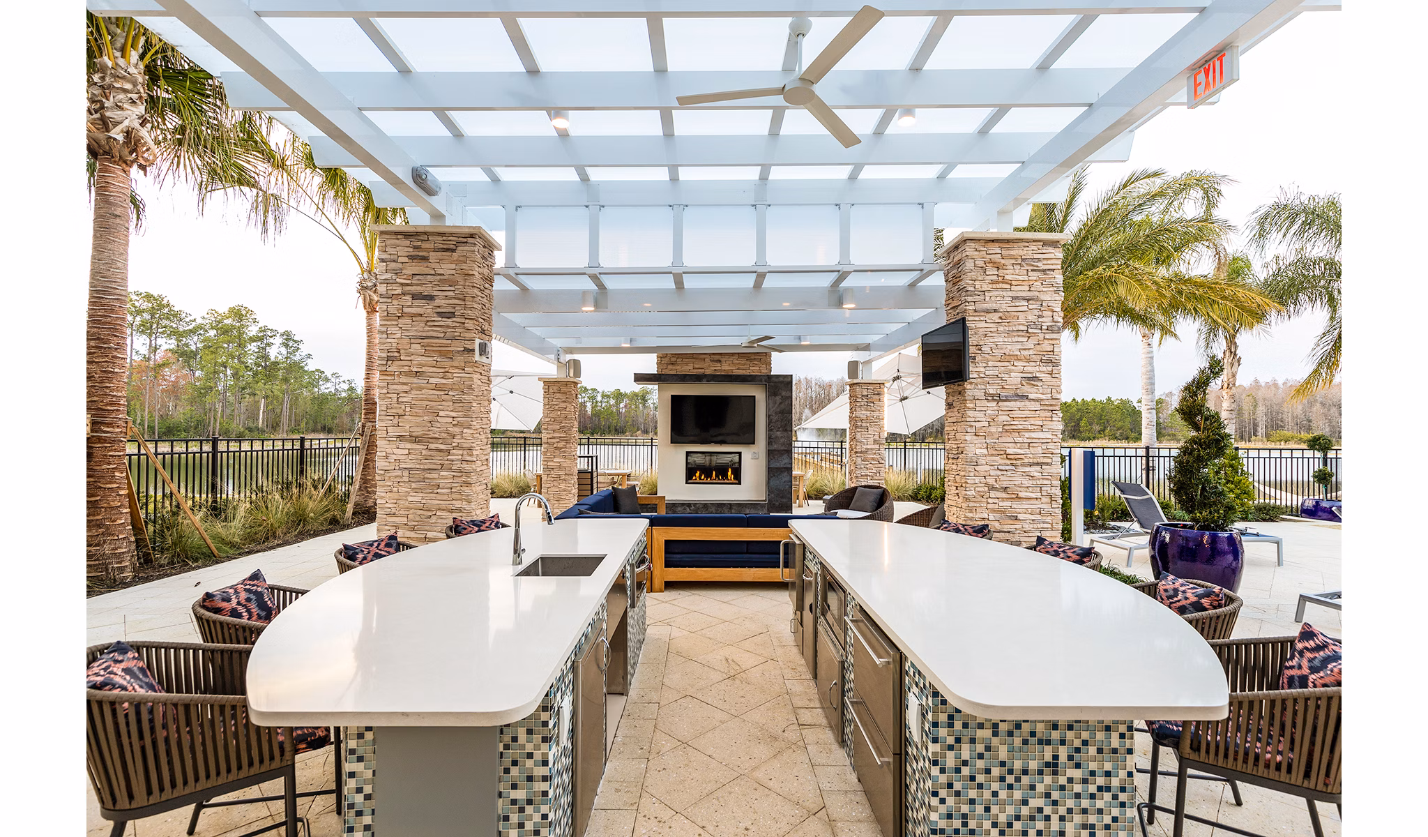 Outdoor pool patio with kitchen and fire pit area at Pier 8 at The Preserve Apartments, creating an inviting space for relaxation and entertainment